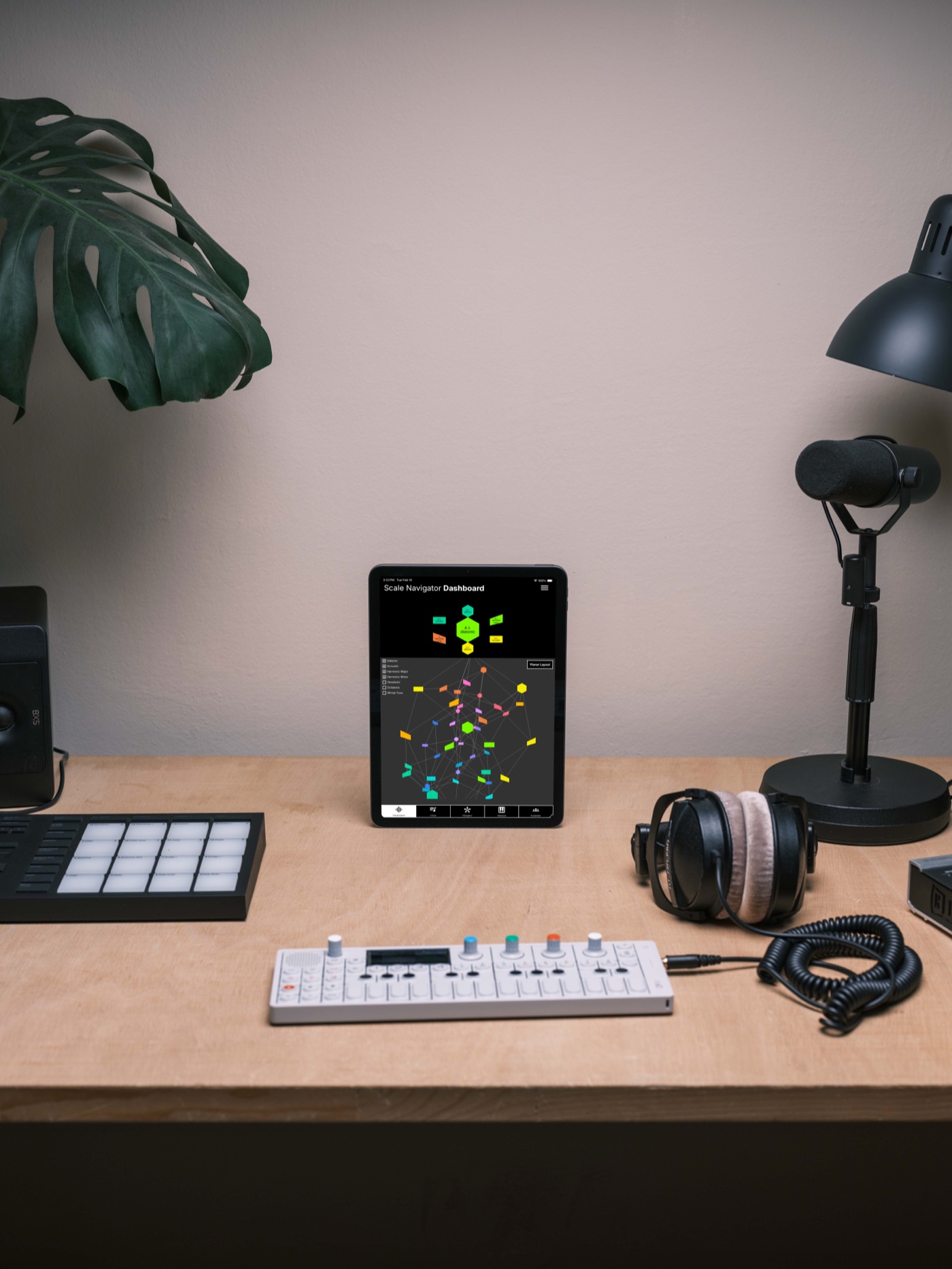 Scale Navigator Dashboard on an iPad standing upright on a studio desk between a pad controller, an OP-1, and headphones