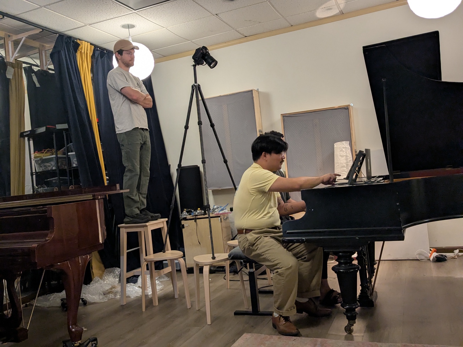 Two musicians sight-reading from a screen score at a grand piano